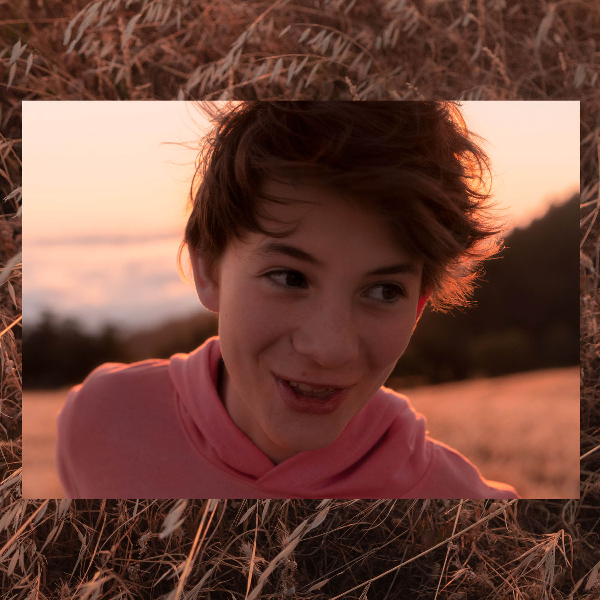 Boy smiling at sunset a top a mountain