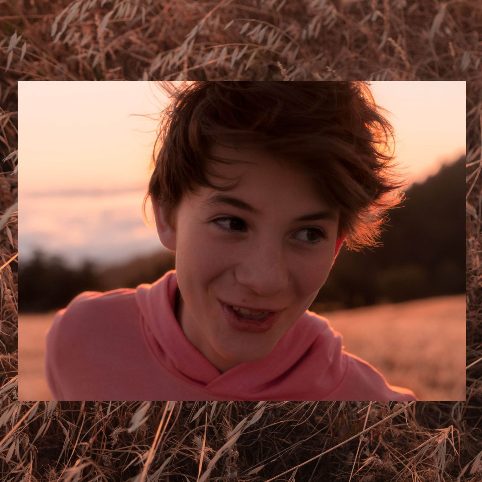 Boy smiling at sunset atop a mountain