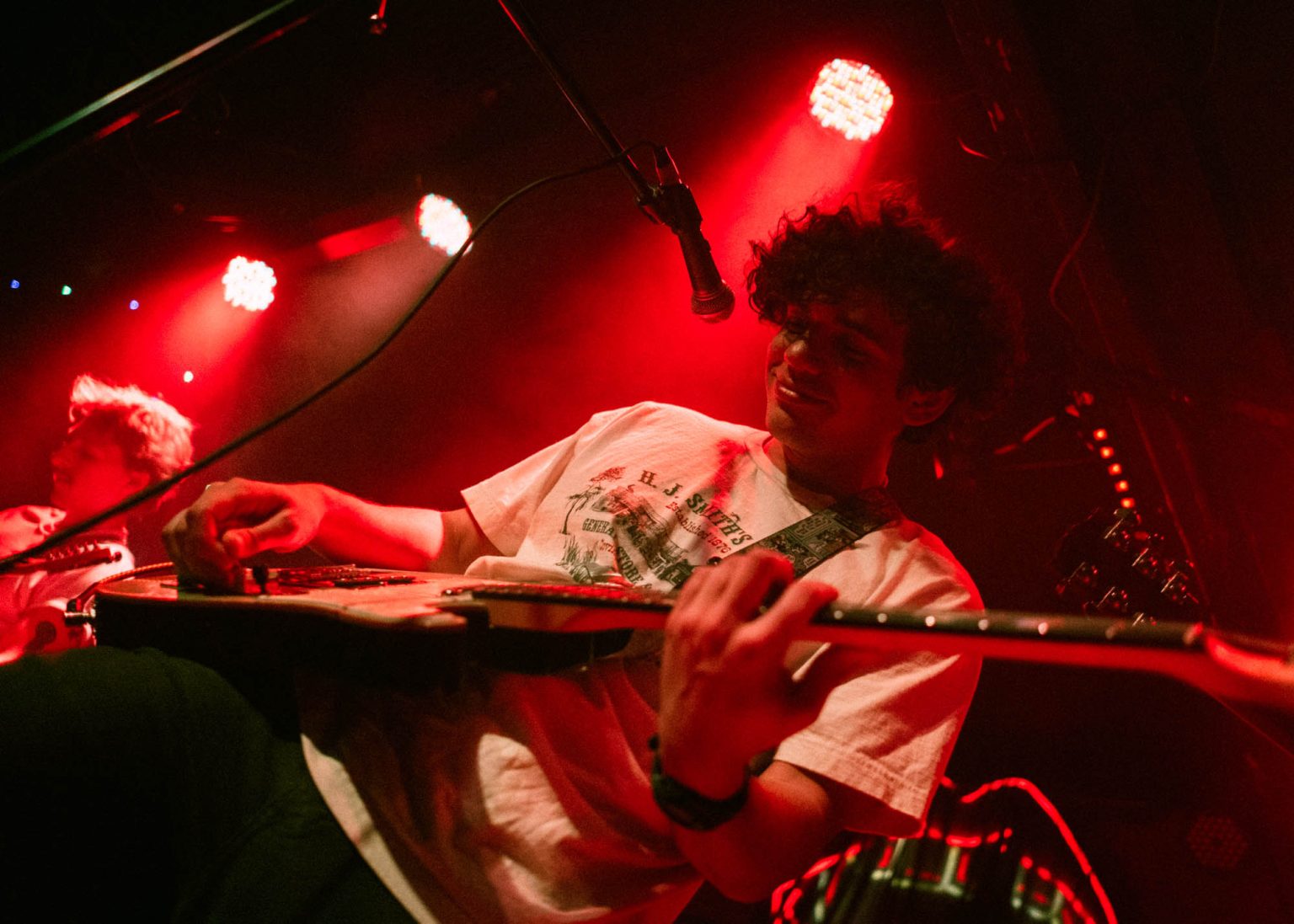 Lead singer playing guitar on stage with his band