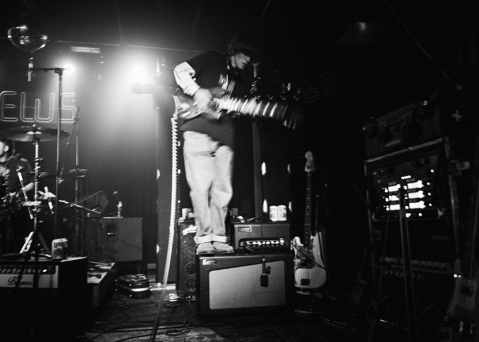 Guitarist playing his instrument awhile standing on top of an amp on stage