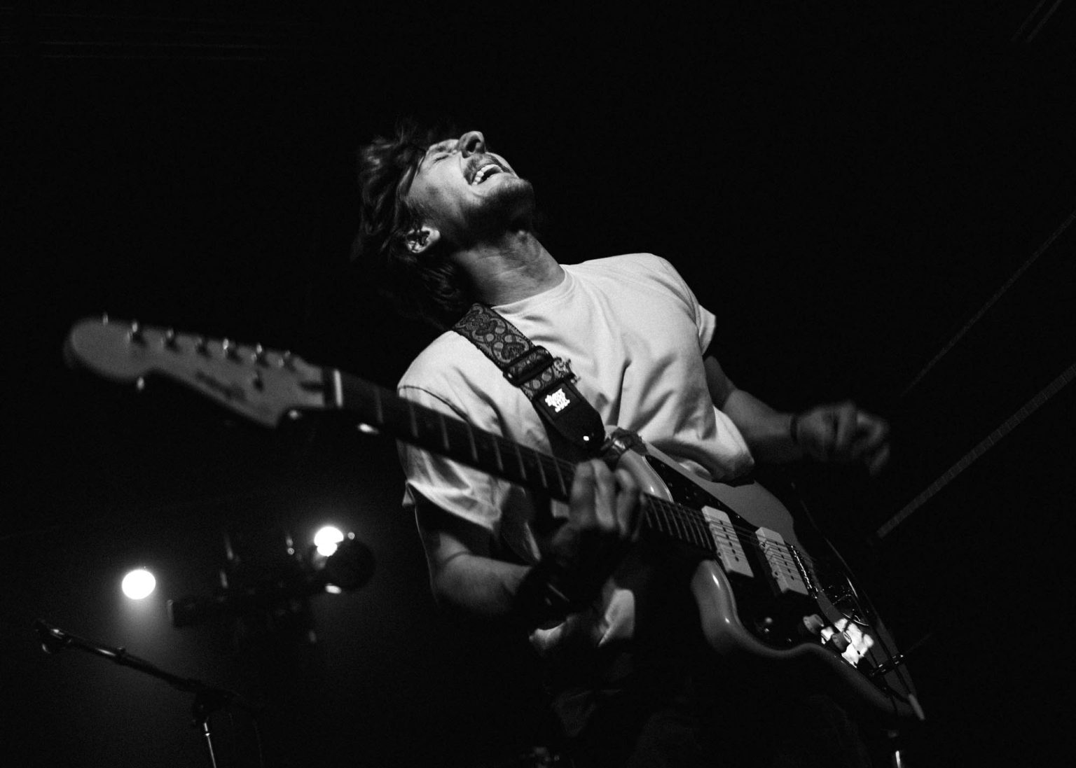 Guitarist in Hotel Burgundy on stage playing notes on his guitar