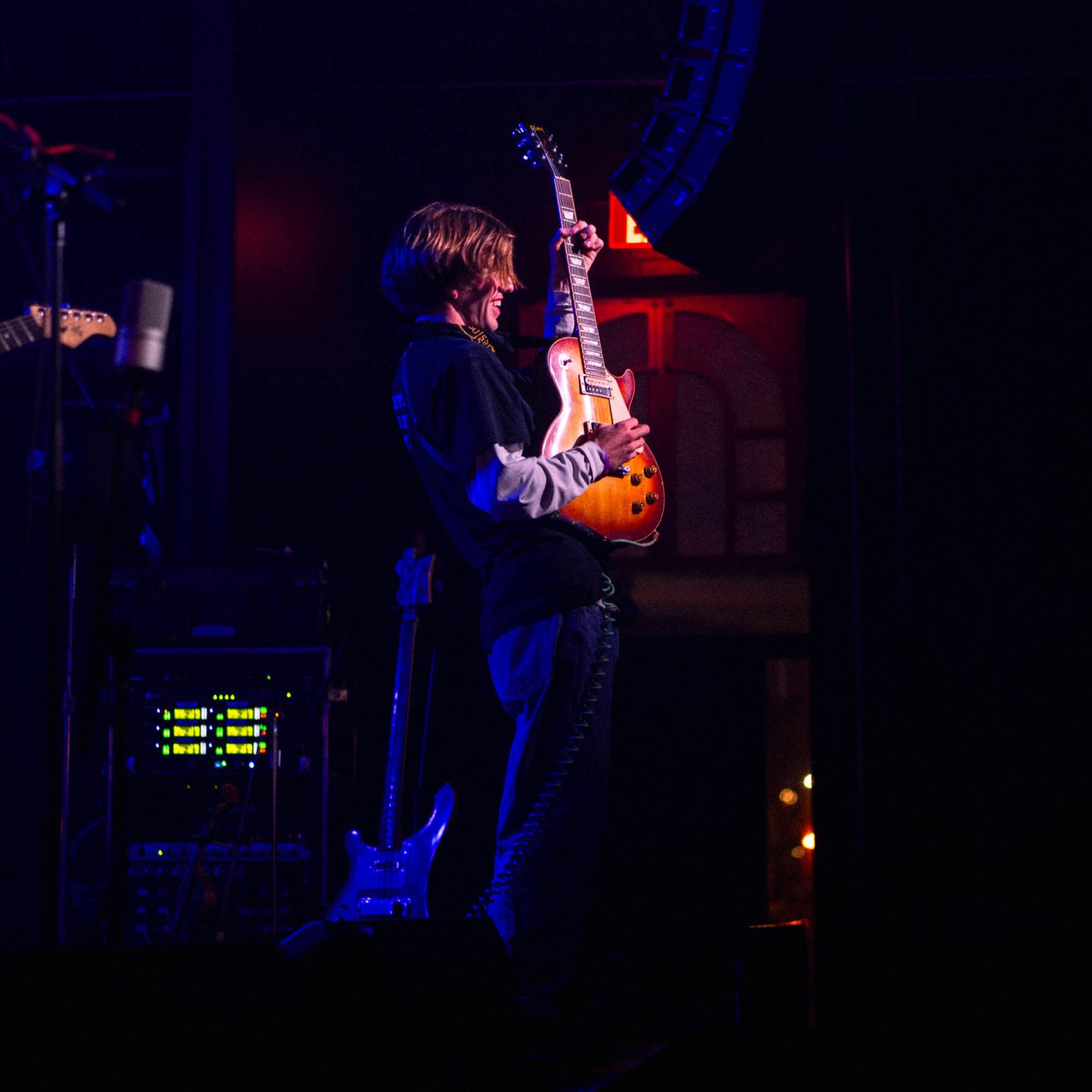 Lead guitarist in Hotel Burgundy on stage raising his guitar up to the crowd