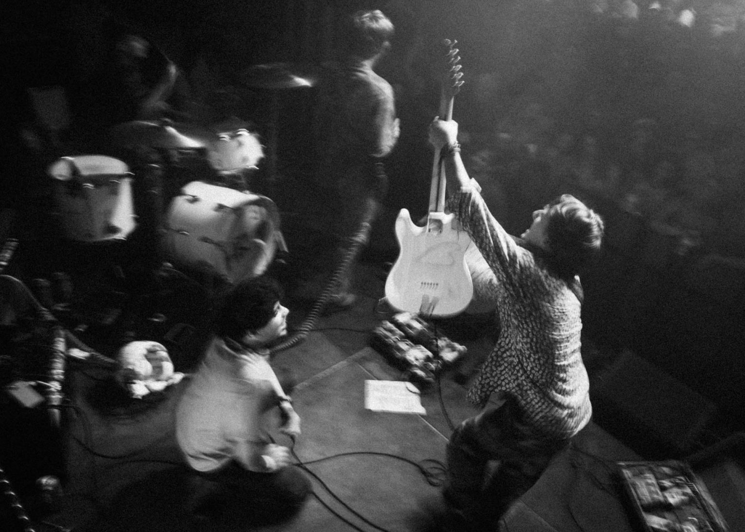 Guitarist running across the stage showing off his guitar while the band continues to make music