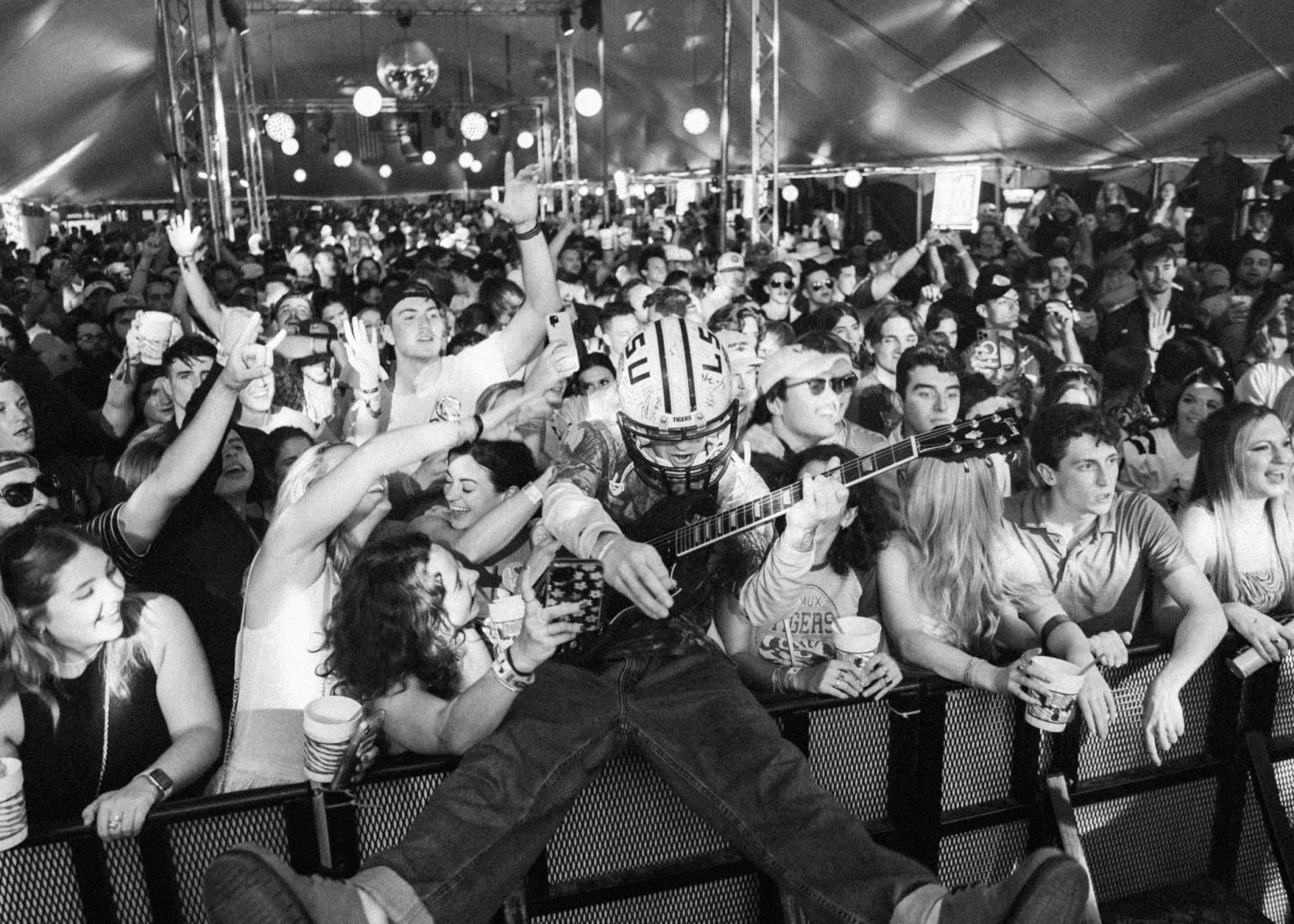 Lead guitarist sitting on the barricade surrounded by the crowd