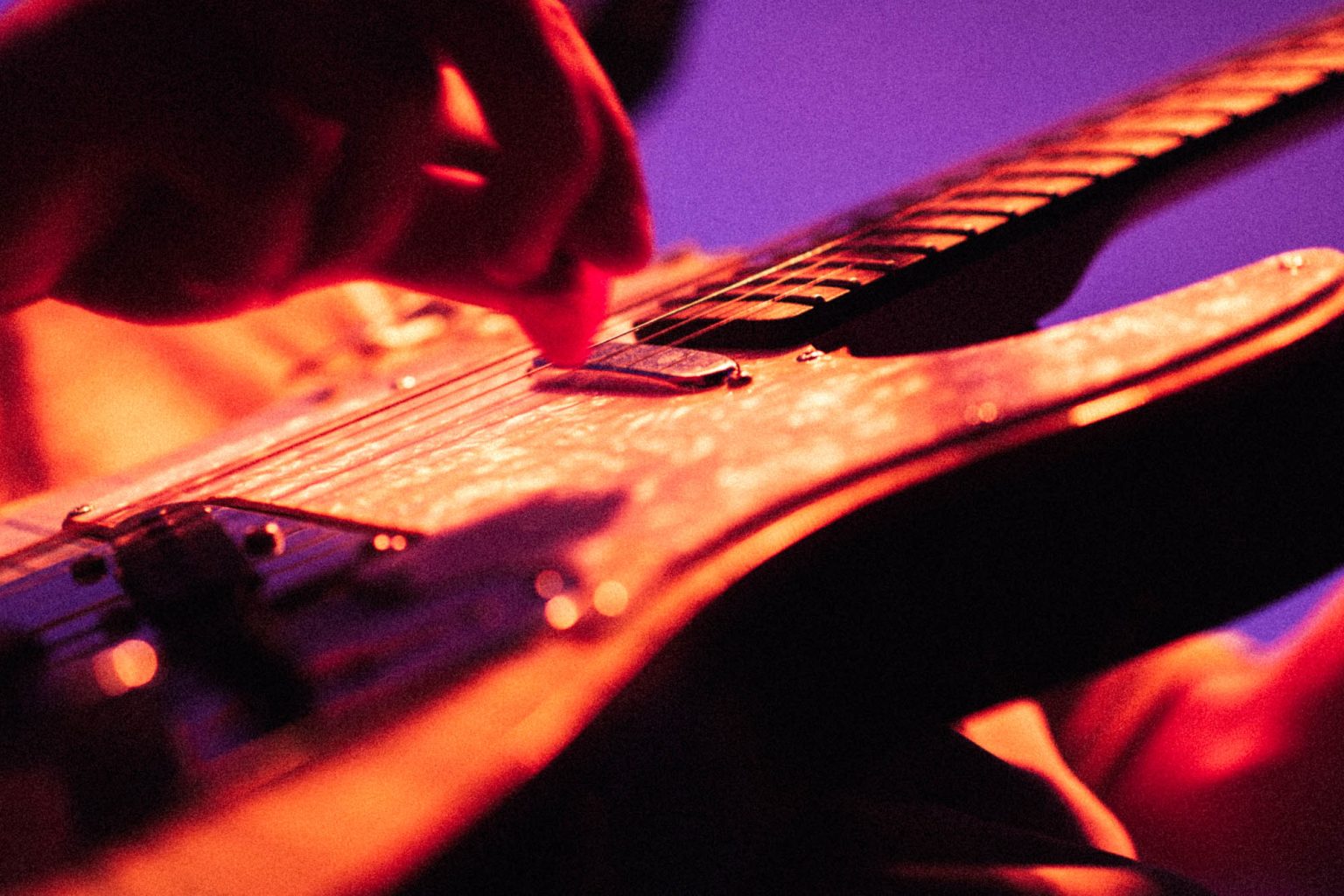 Close-up of a guitar being played on stage