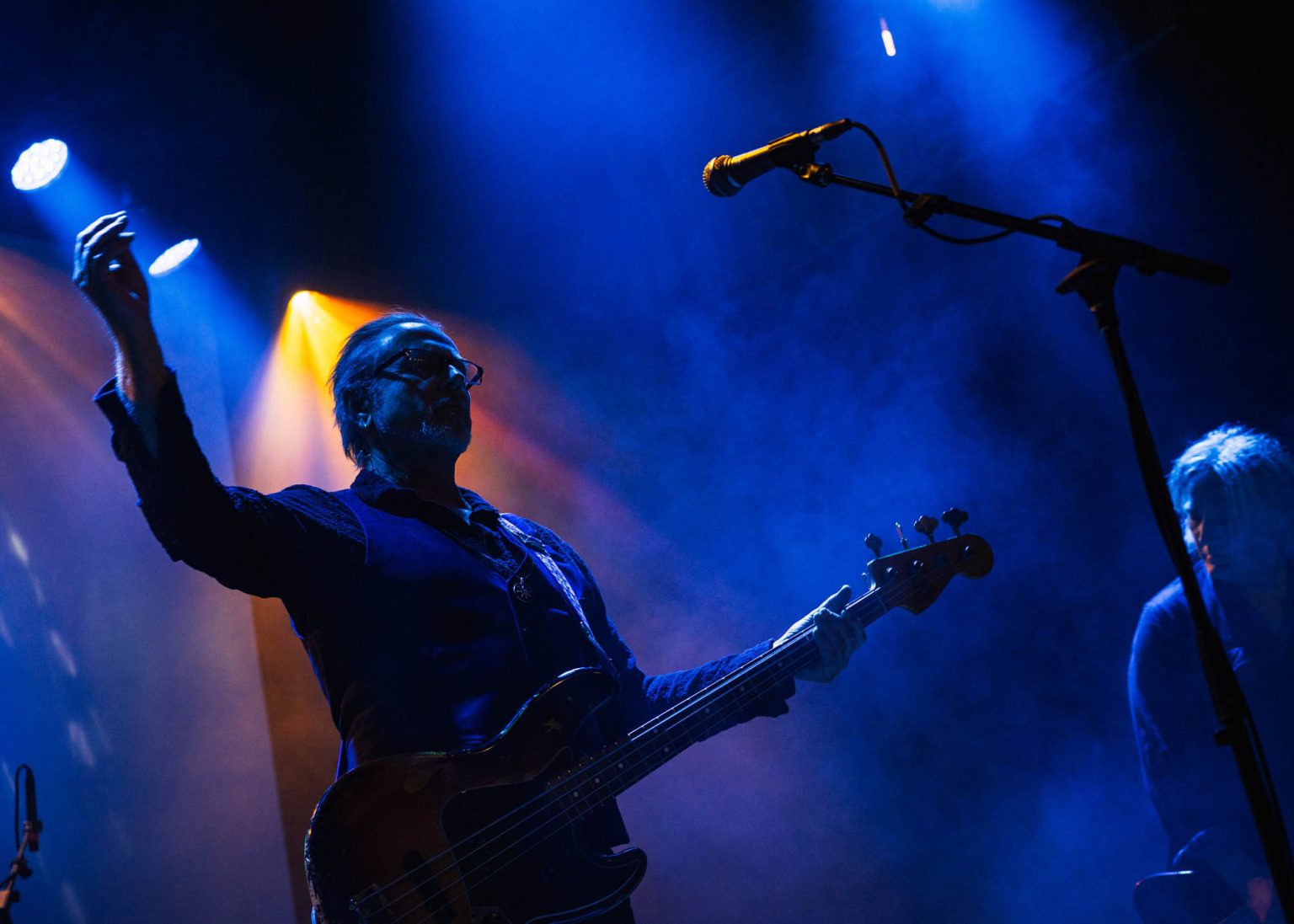 Lead singer with guitar on stage arms stretched out living up the music they are creating