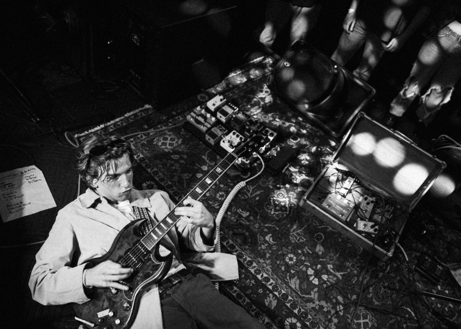 The lead guitarist of Hotel Burgundy on the floor playing his guitar at Carrollton Station