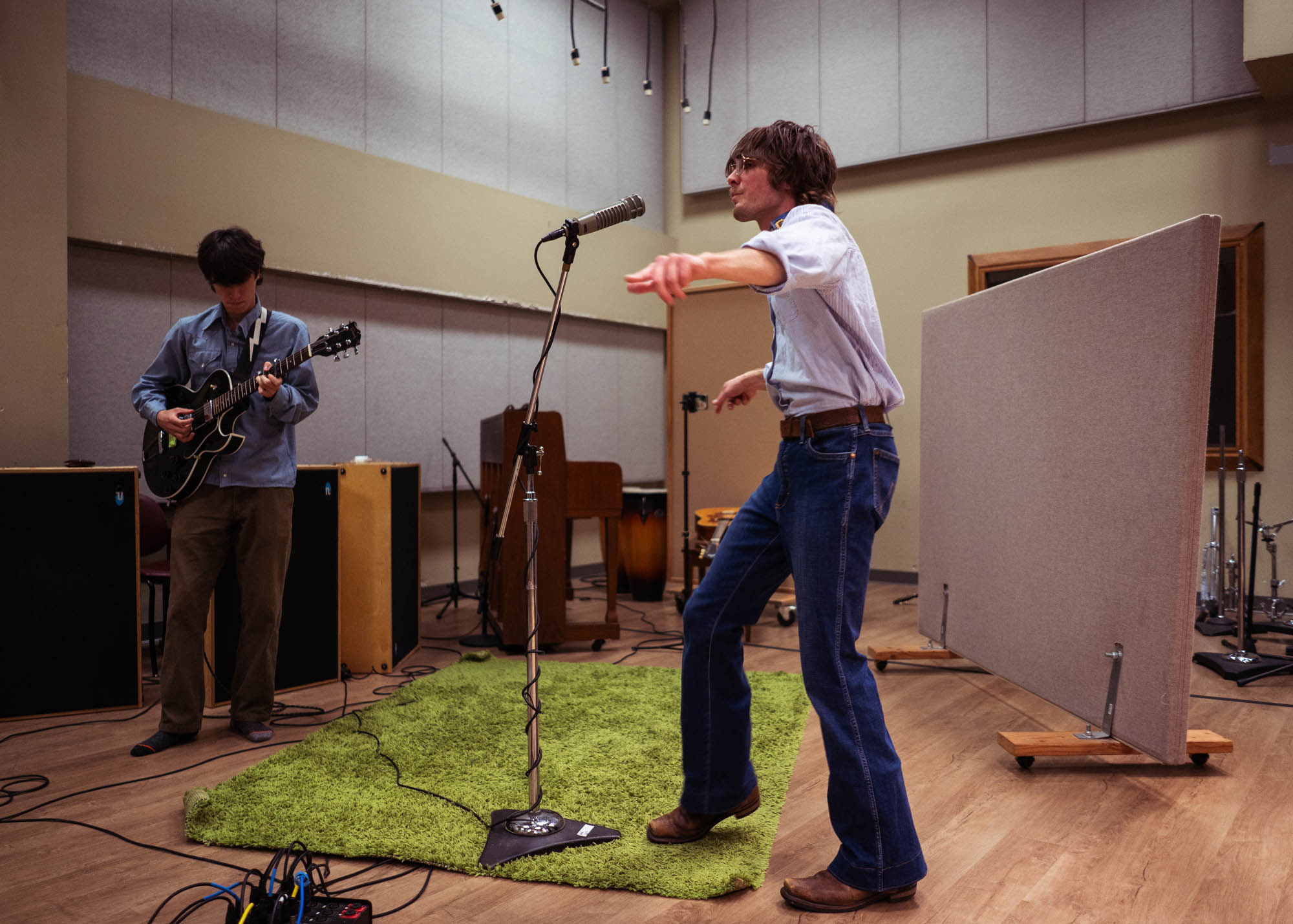 Dancing while singing a new song in the recording studio with the guitarist in the background