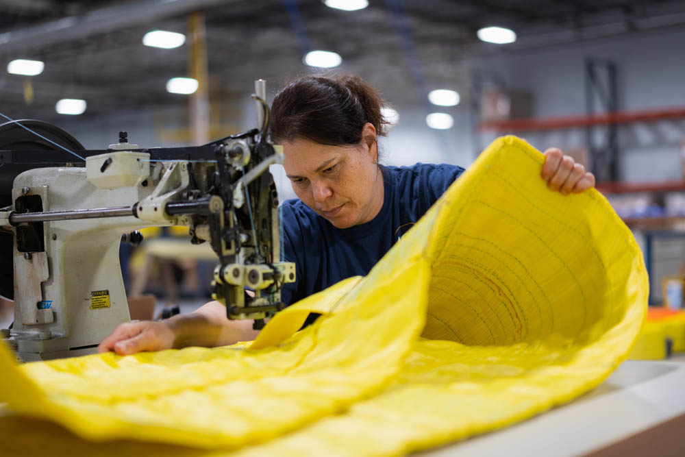 At the sewing machine working on creating a yellow sling and rigging product