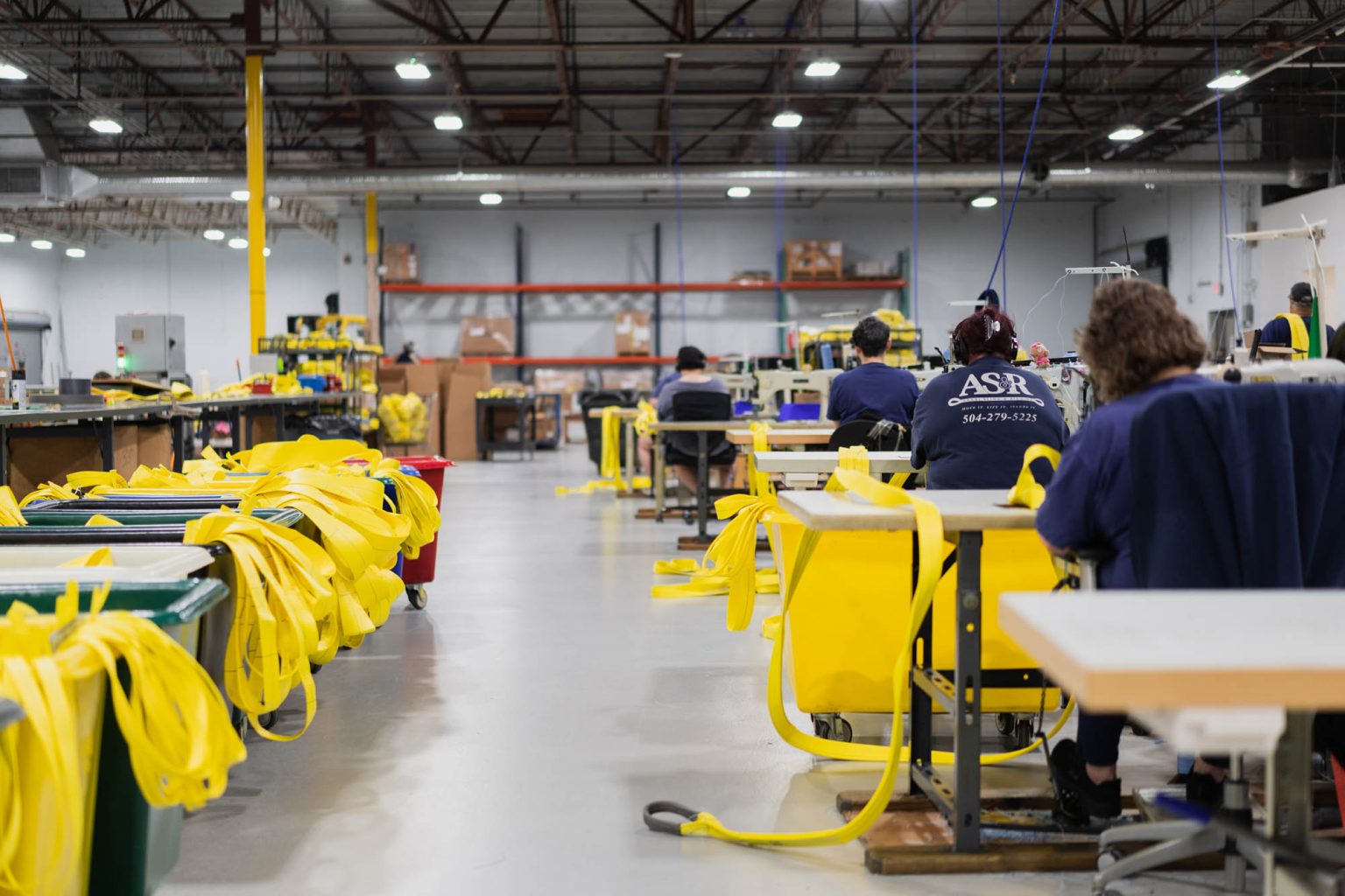 Aisle of team working at sewing machines creating yellow sling products