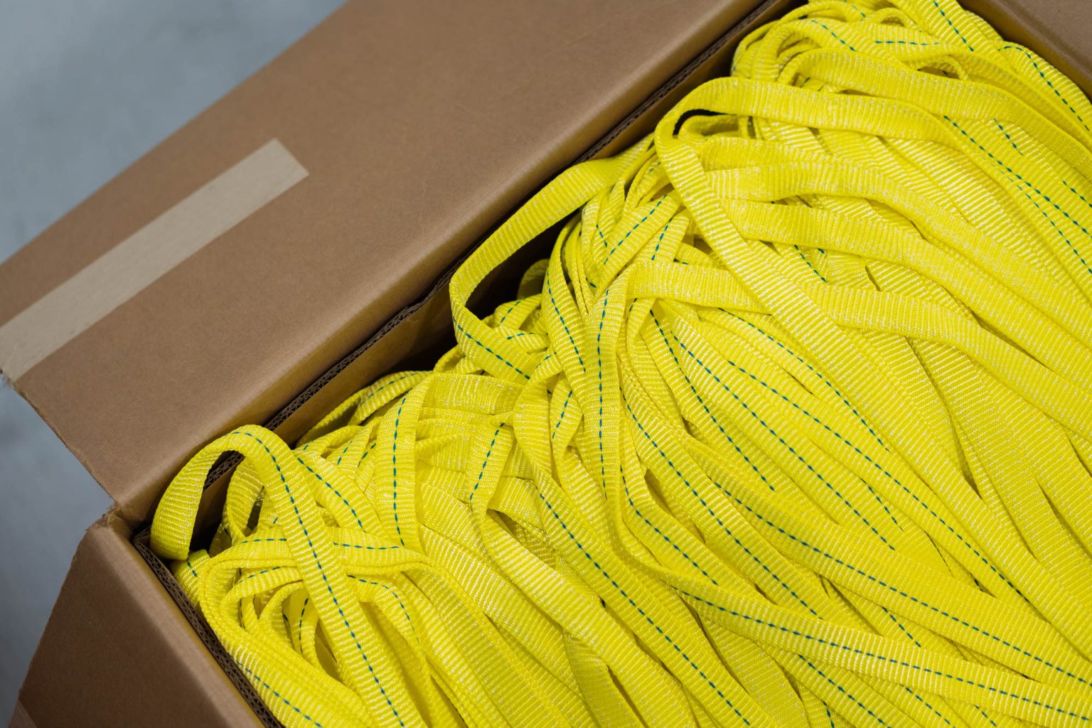 Box full of yellow slings with blue threading