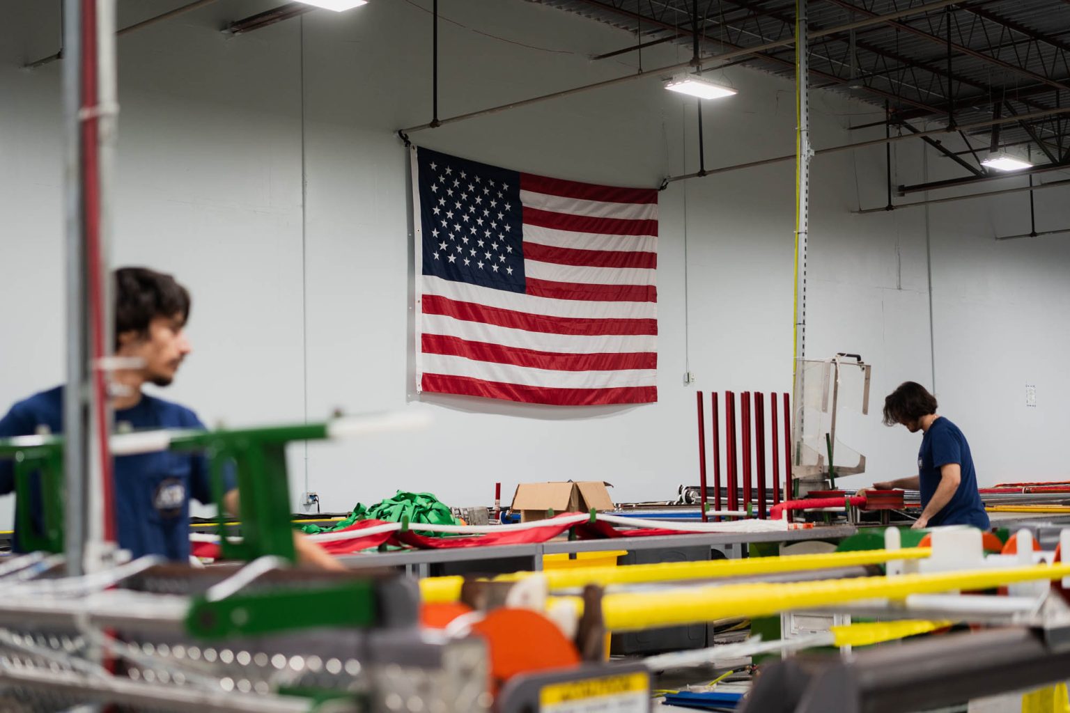 American flag hung on wall with team members working in the foreground creating sling and rigging products