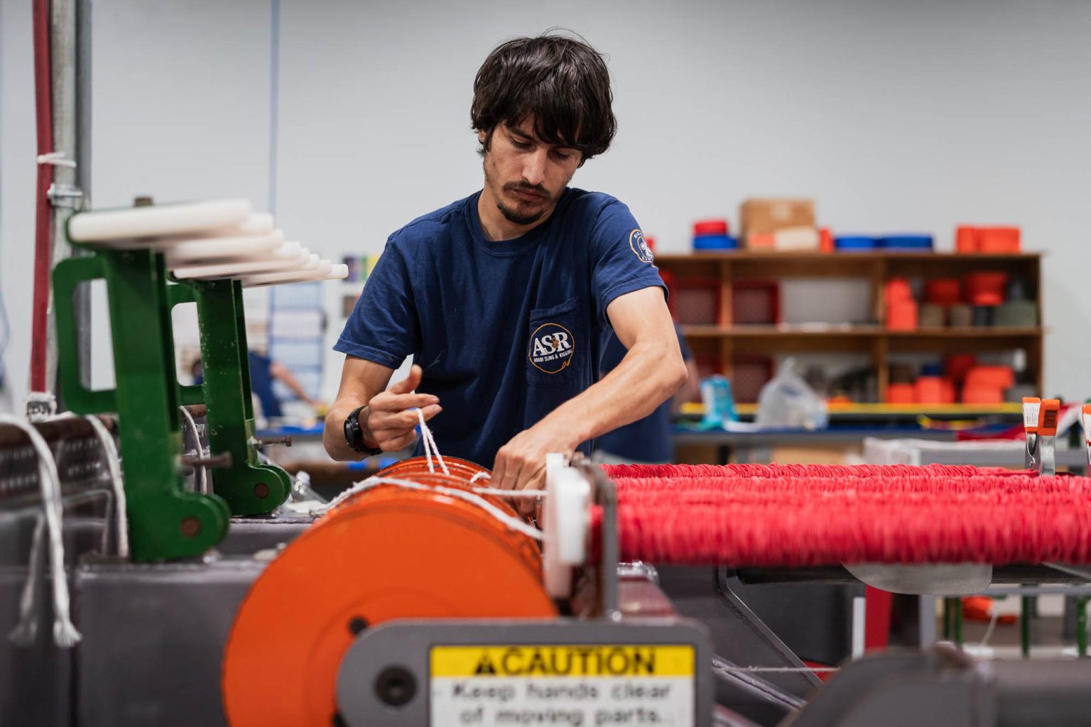 Team member working on the production line creating red polyester round slings