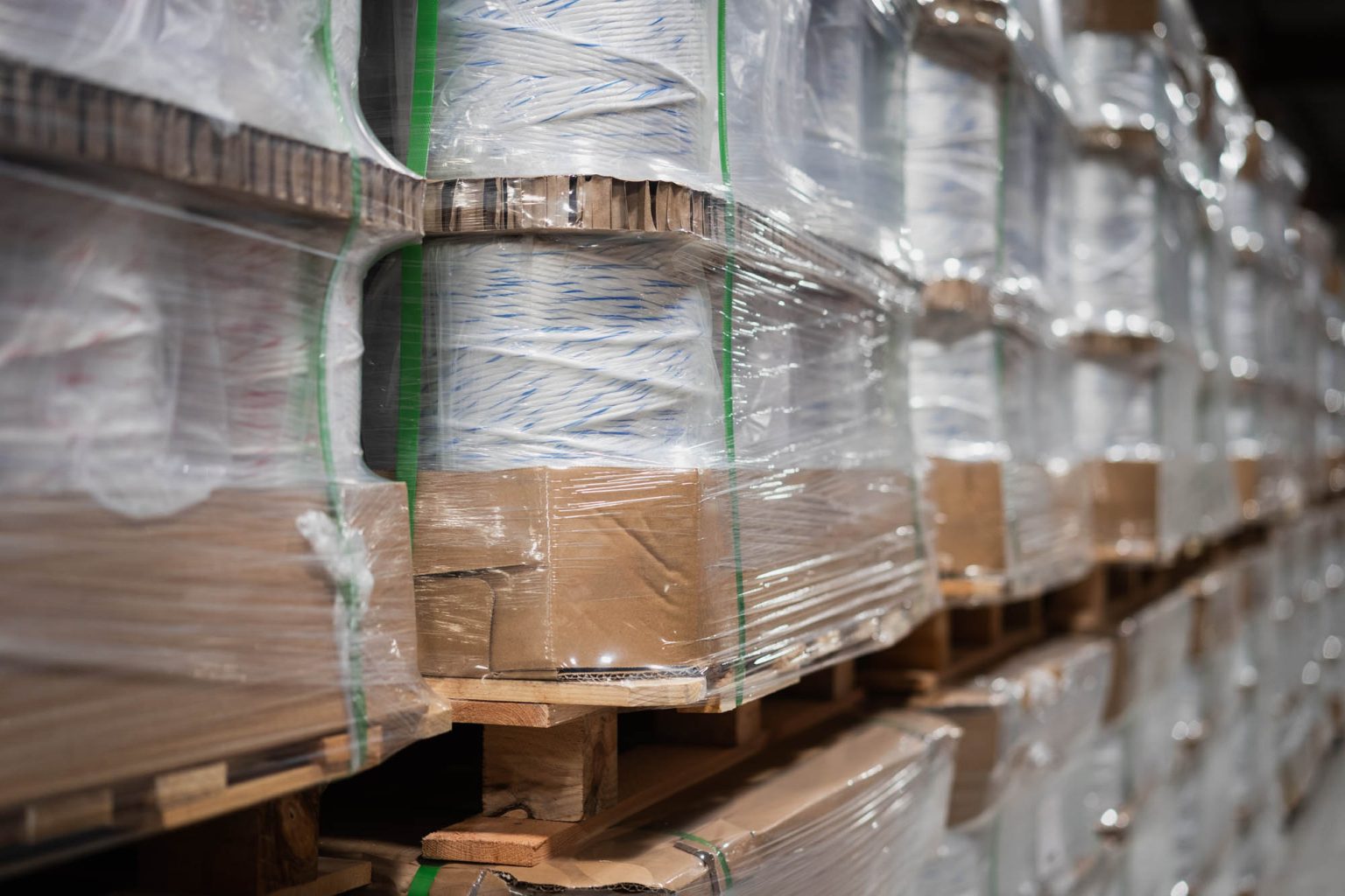 Row of rolls of yarn in packaging on pallets