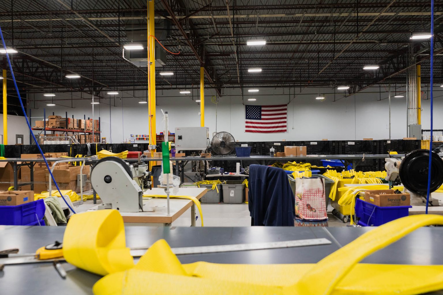 Large facility used for creating sling and rigging products with American flag on wall in the background