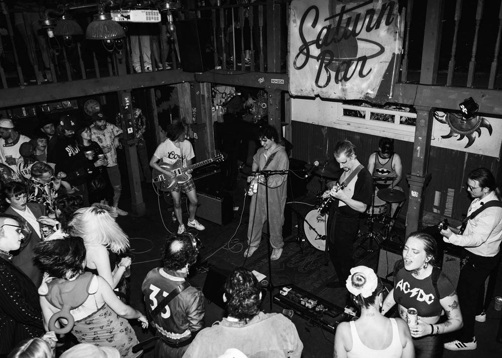 Band on stage playing for a crowd dressed in Halloween costumes