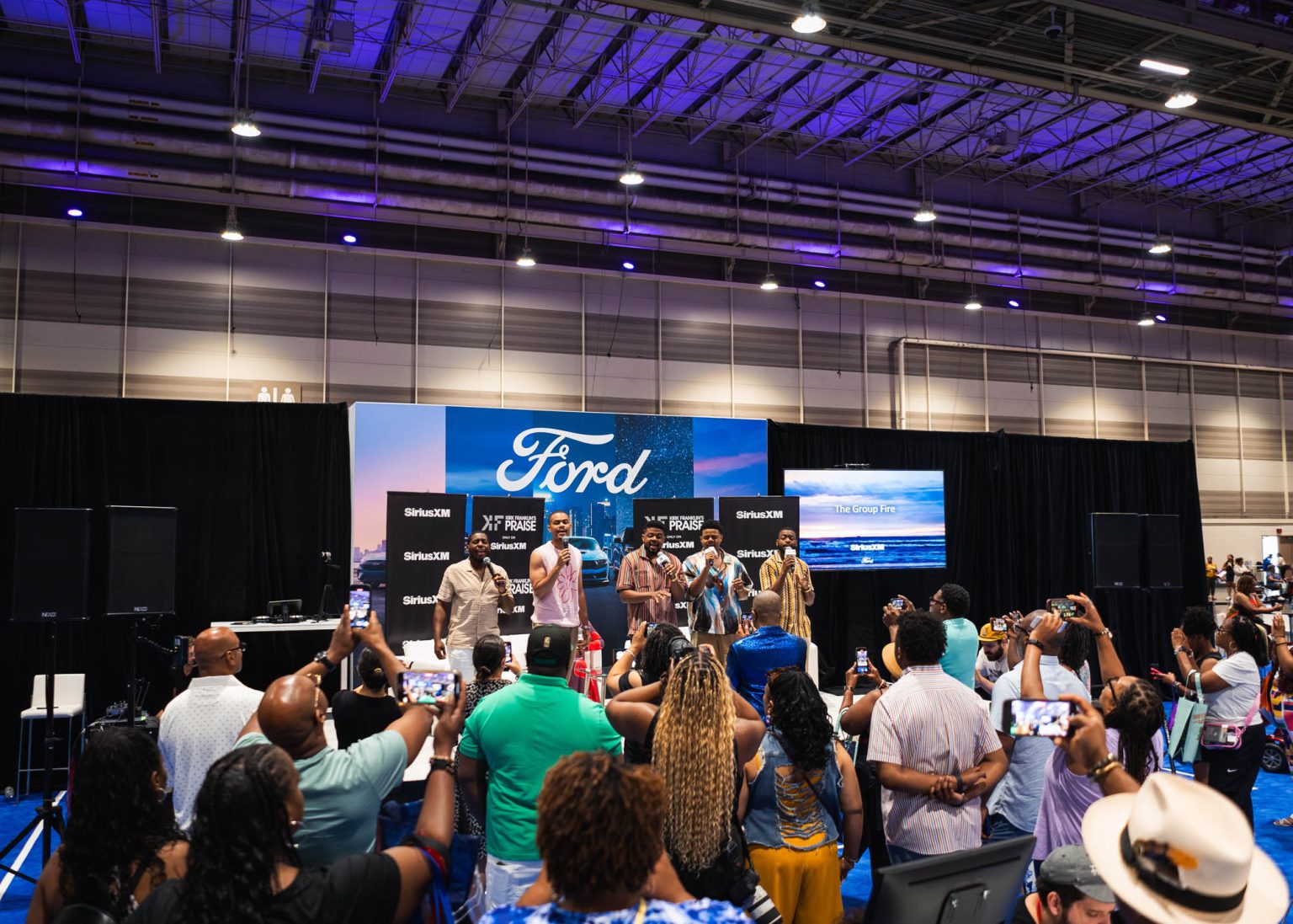 Band singing on stage with bustling crowd at the convention center