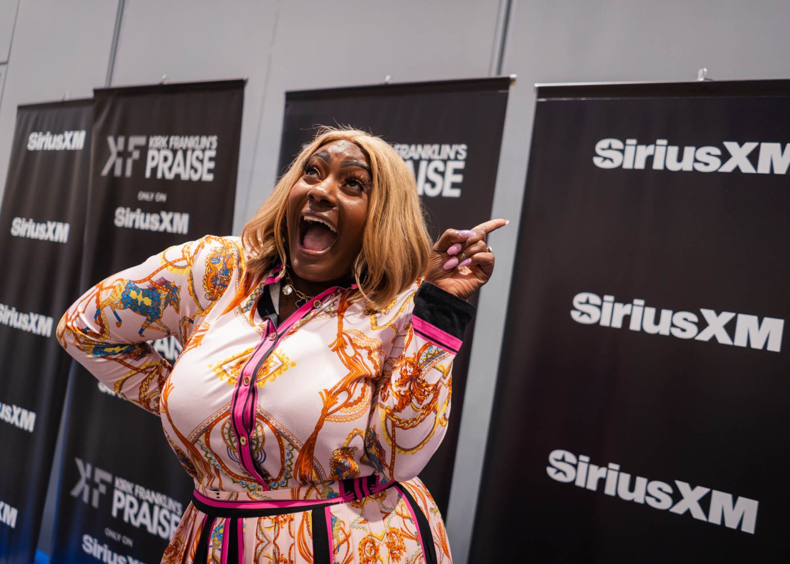 Number one hand signal posing for a portrait back stage with SiriusXM banner in the background