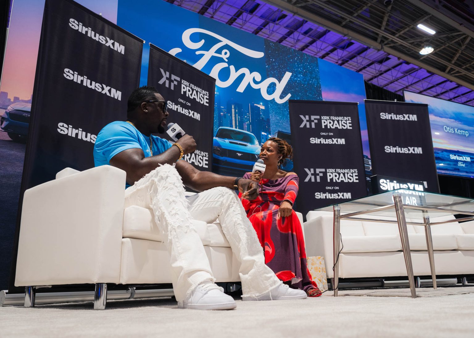 On stage artist talking with the interviewer while sitting on couches