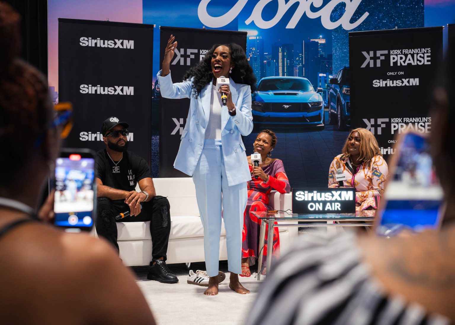 Fans filming on their phones as singer in a lite blue suit performs live on stage