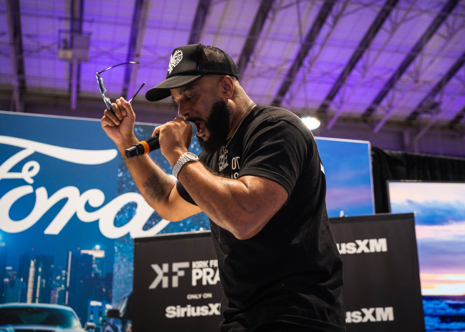 Singer taking his sunglasses off and performing on stage with a microphone