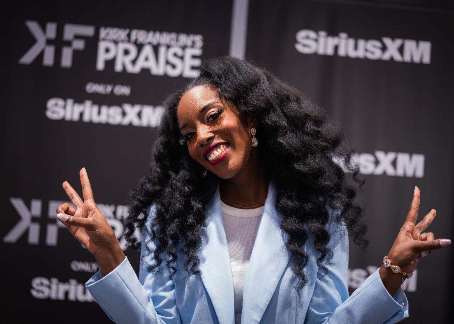 Peace signs and smiling for a portrait with Kirk Franklin's Praise banners in the background