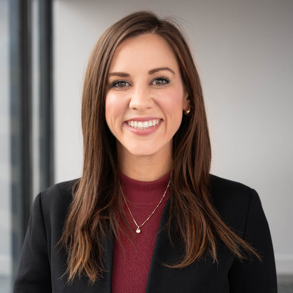 Lawyer smiling near a window and she's standing in a high rise