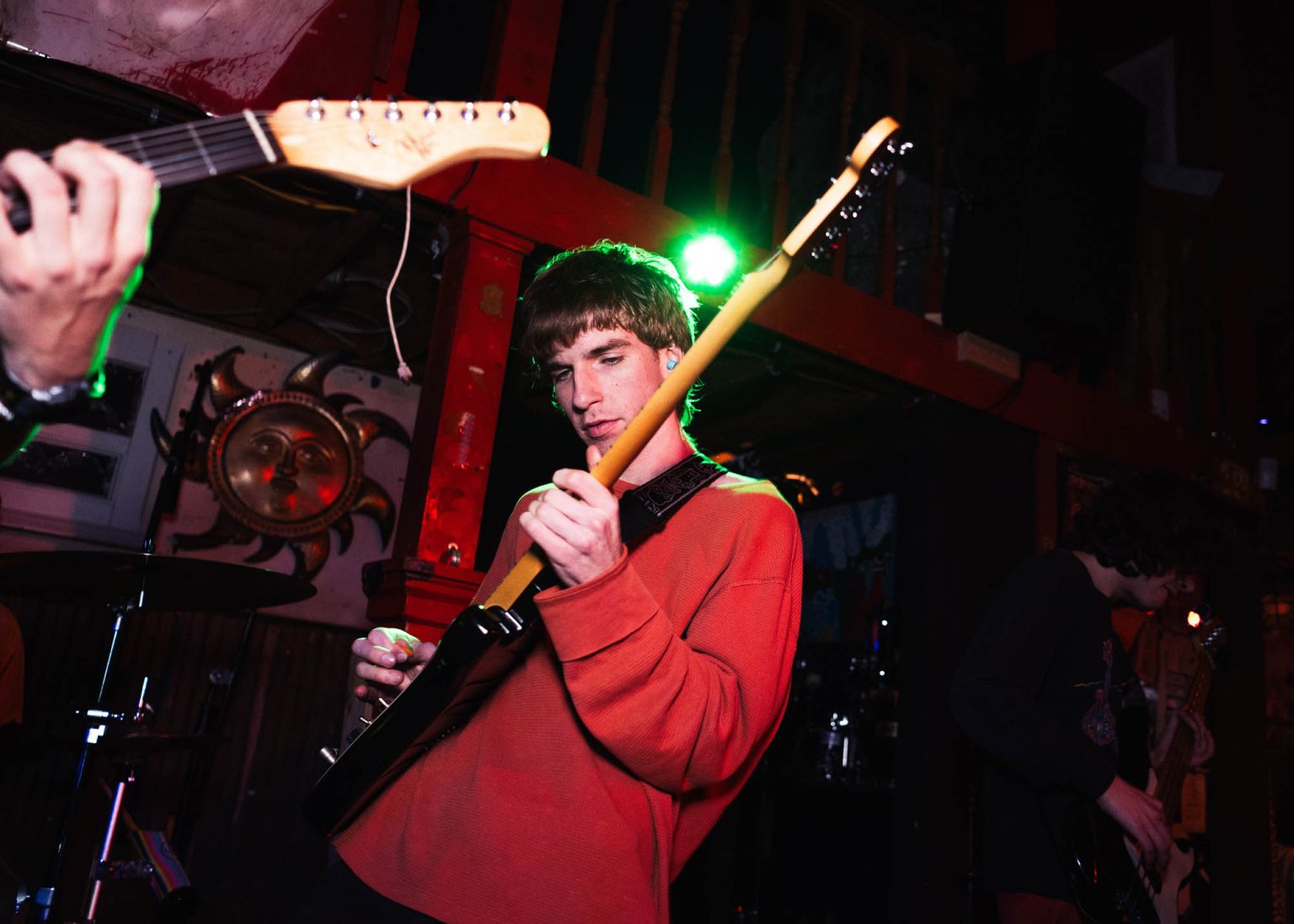 Guitarist on stage playing instrument surrounded by fellow band mates