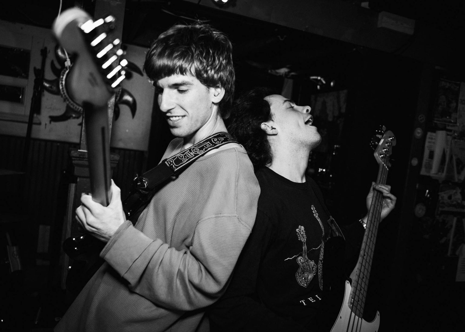 Bassist and guitarist standing back to back while playing their instruments during a live concert