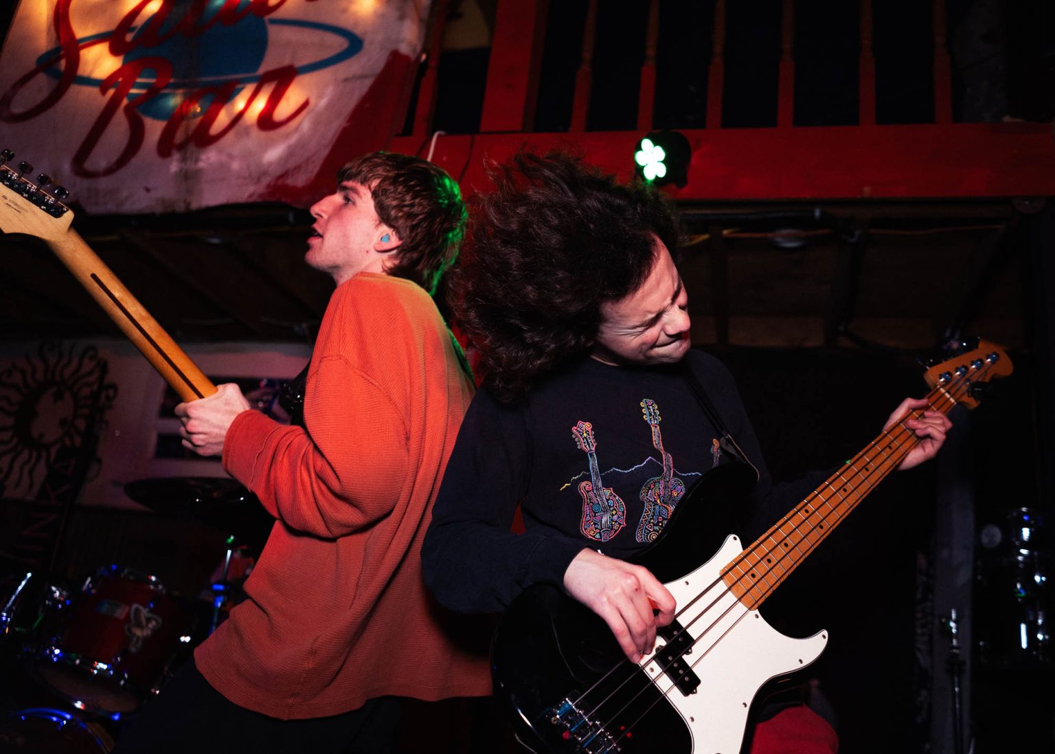 Guitarist and bassist on stage standing back to back while playing instruments on stage