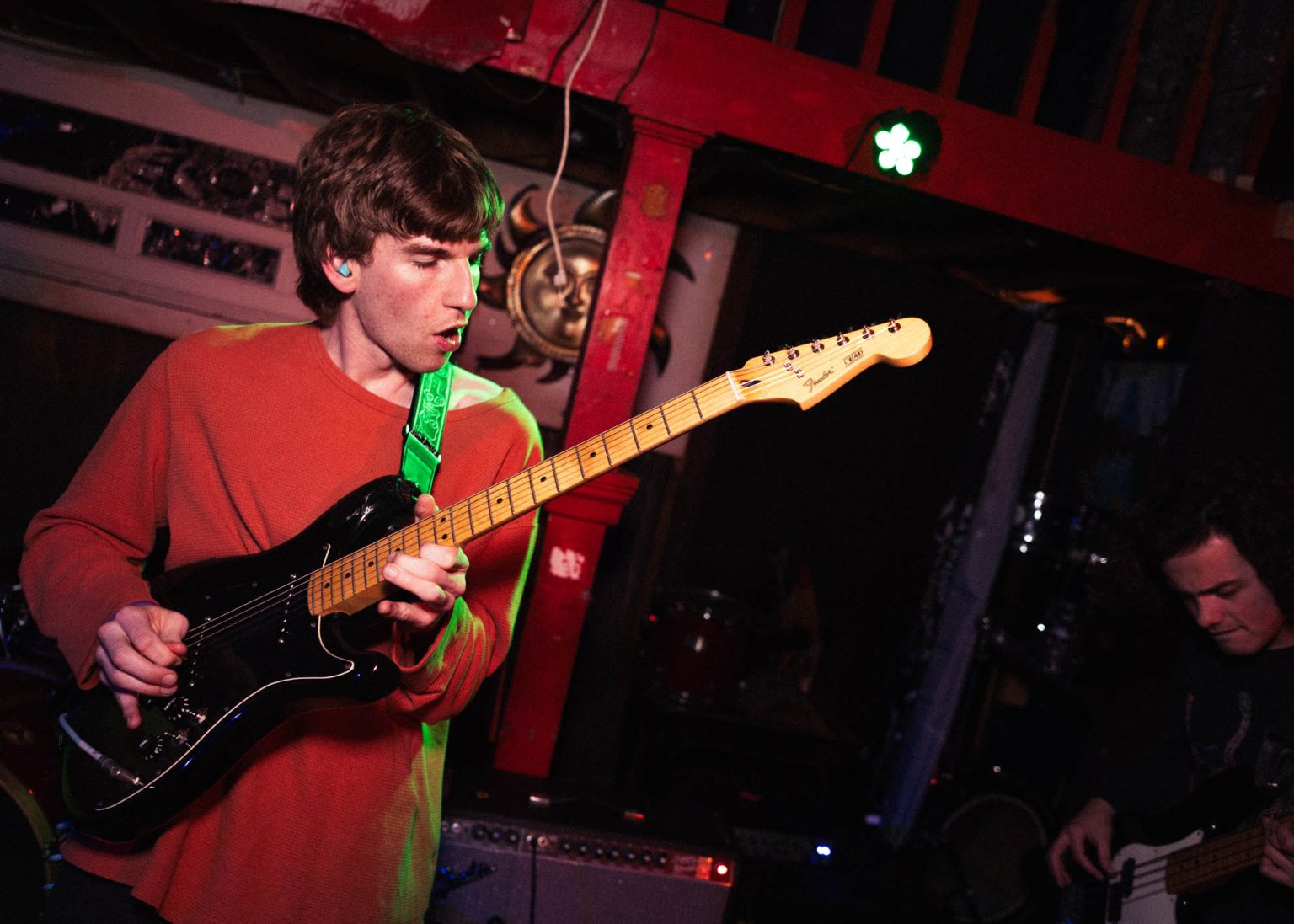 Guitarist on stage with his eyes are closed focused on playing his instrument bassist off to his side playing instrument as well