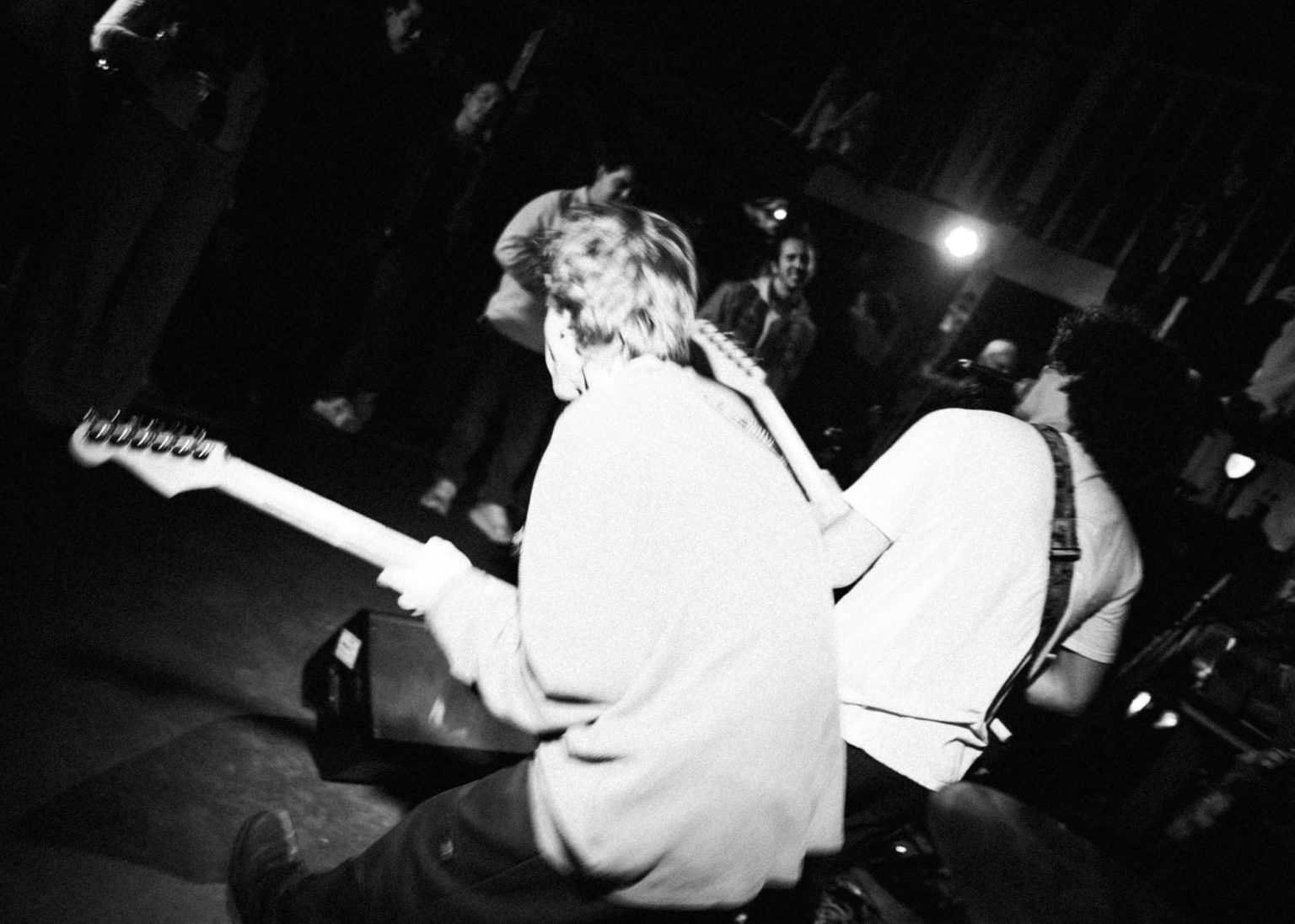 Guitarist dancing next to lead singer while on stage with crowd in the background