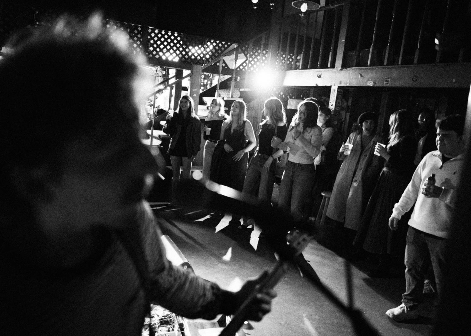 Guitarist singing into microphone in the foreground and bustling crowd in the background