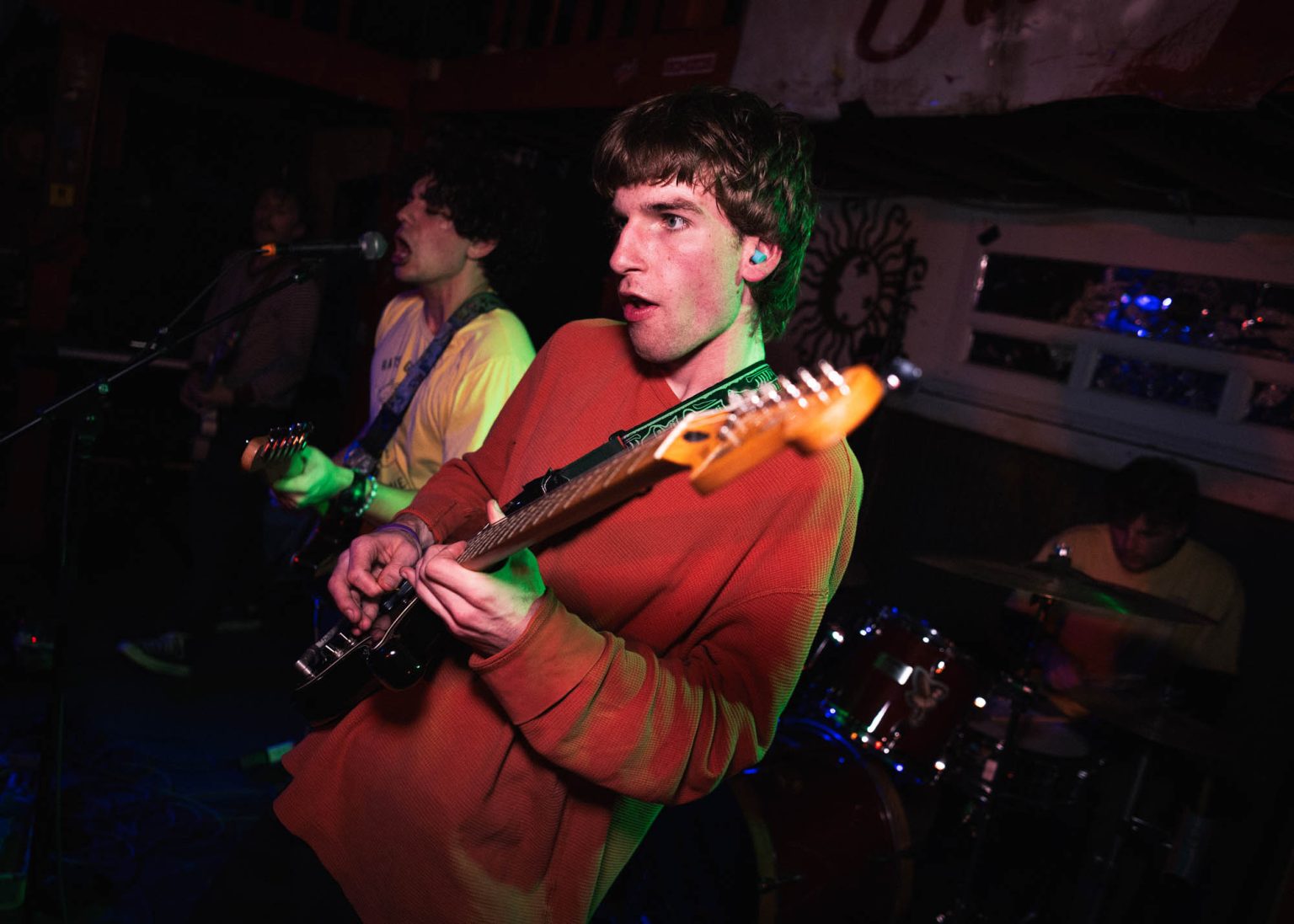 Guitarist playing guitar with fellow band mates in the background