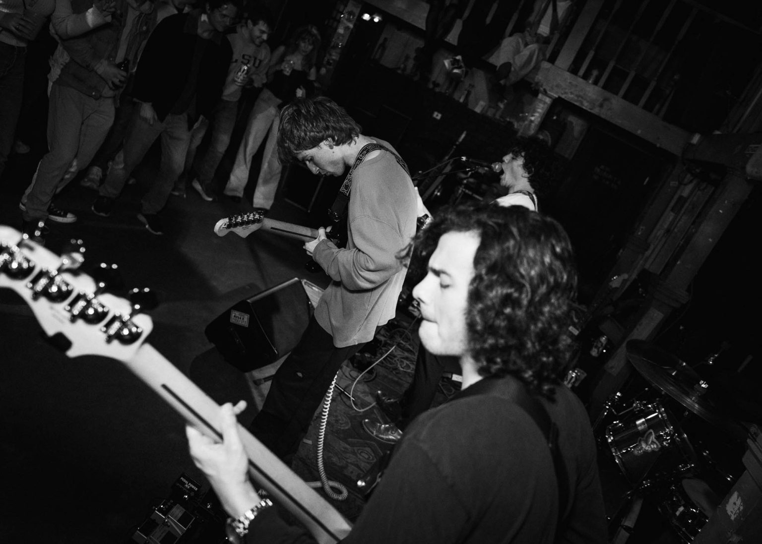 Guitarist, bassist, lead singer on stage and crowd enjoying the concert