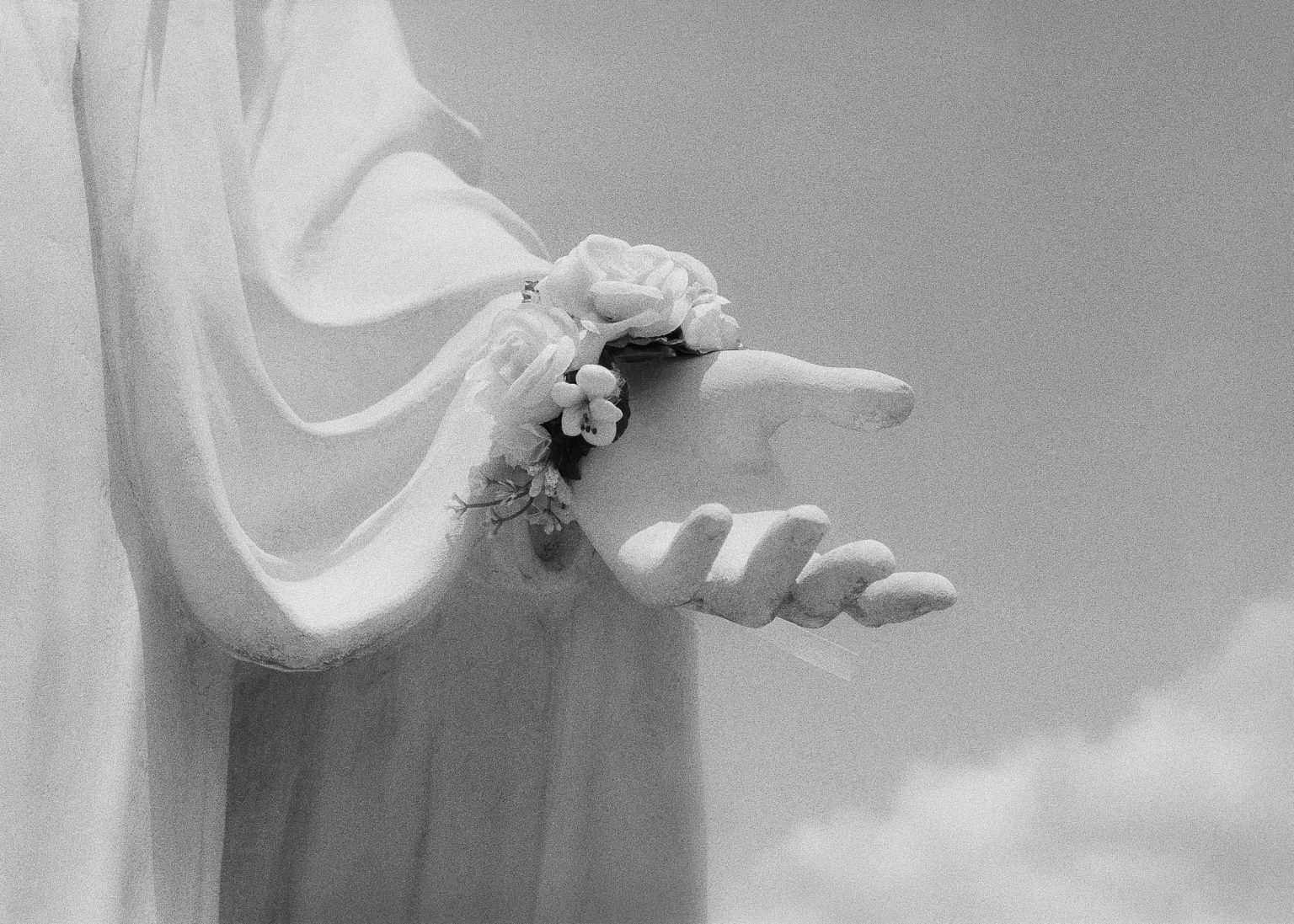 Hand of Mother Mary statue with flower bracelet on her wrist in a New Orleans cemetery 