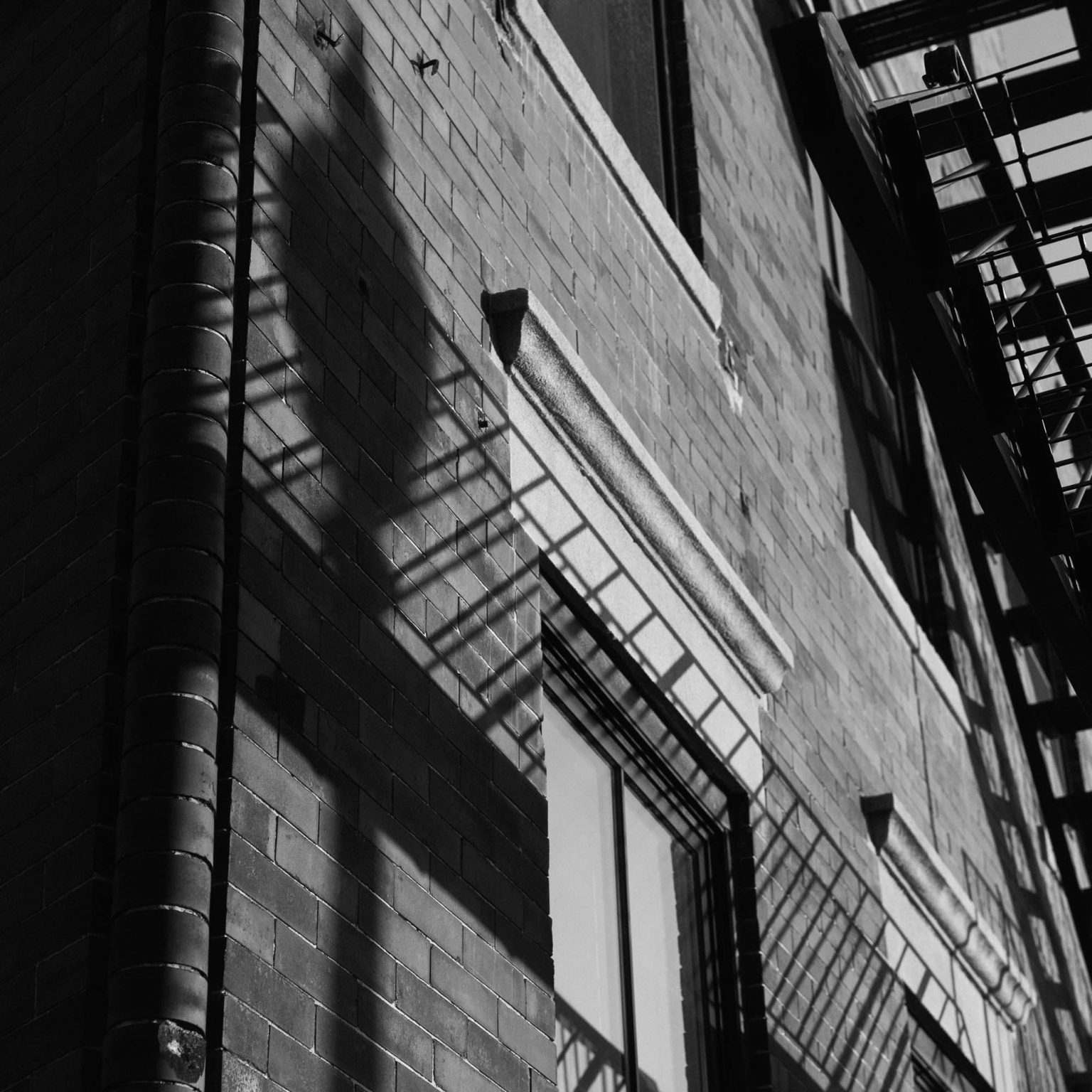 Shawdow of a lamp post against a brick building in Boston