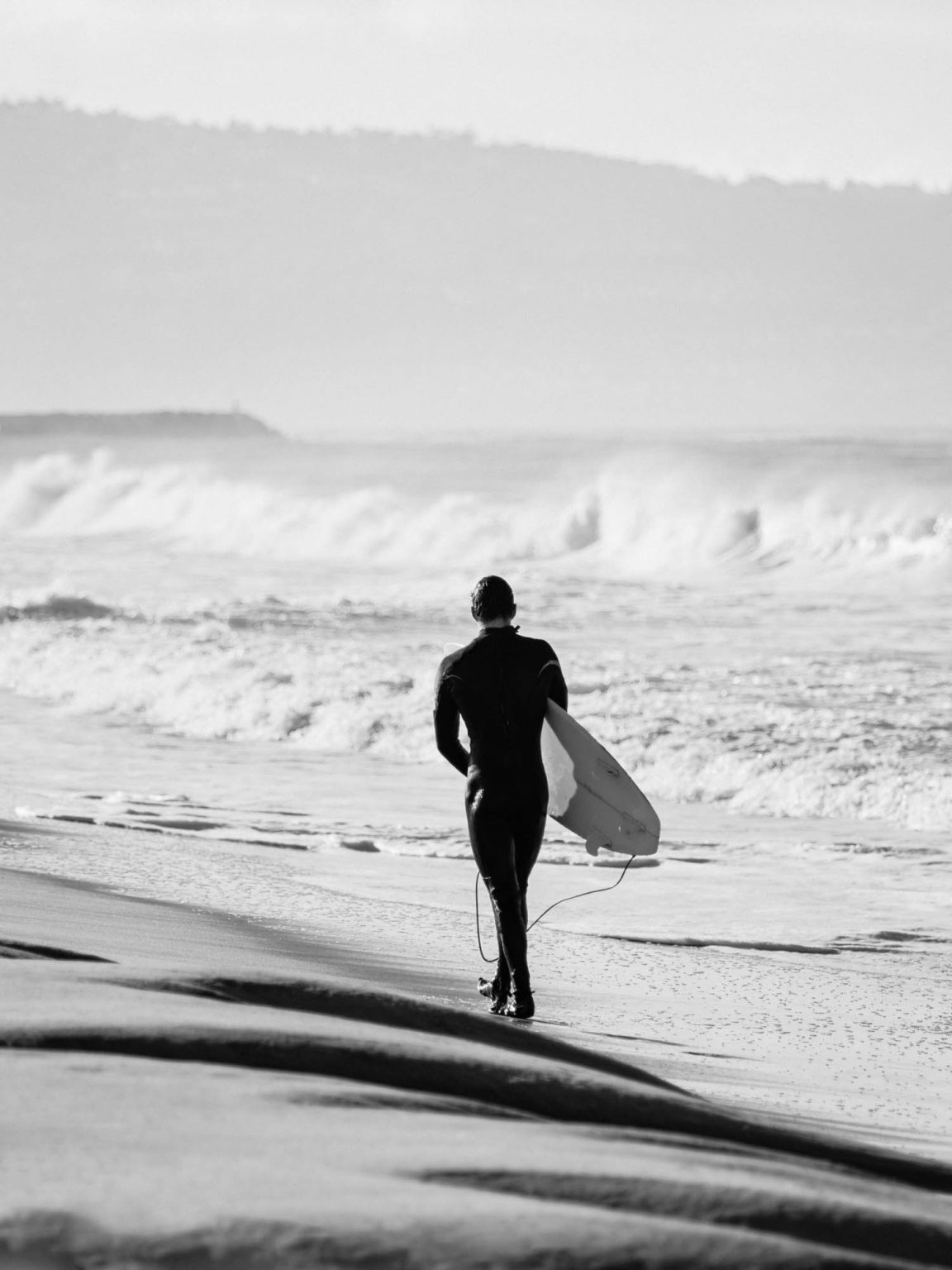 Sufer walking with his board along Hermosa Beach coast in California